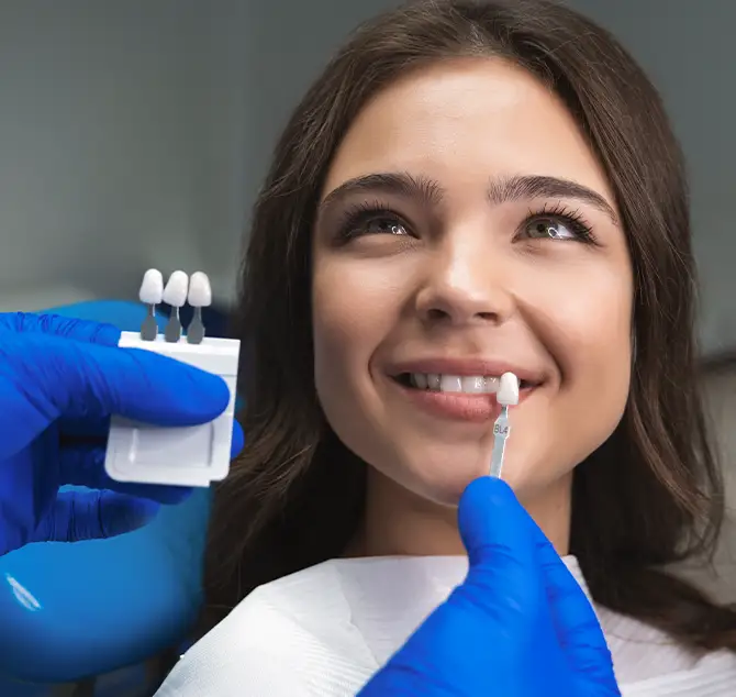 Arzt hält Veneers gegen die Zähne einer Patientin