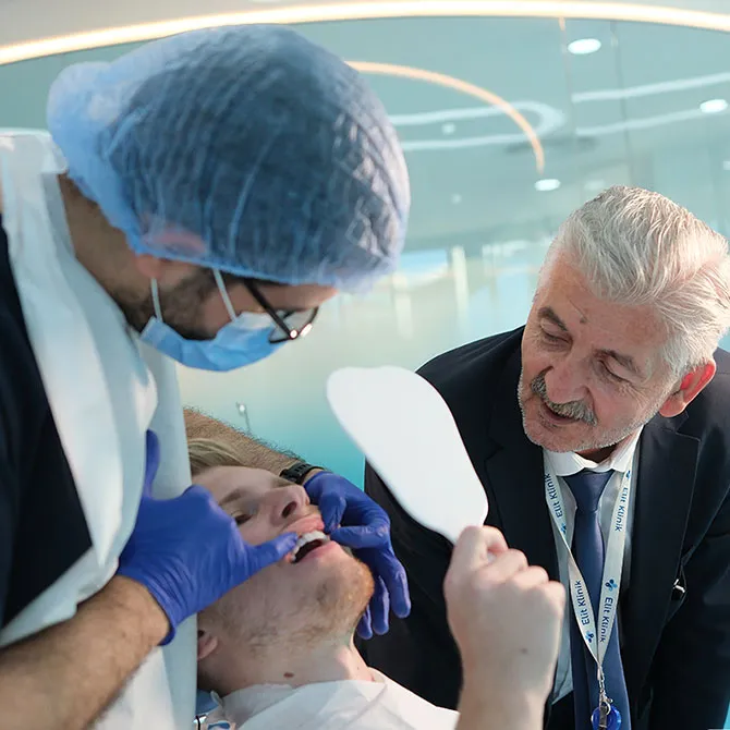 Bild zeigt eine YesSmile Patientin, die sich ihre neuen Zähne im Spiegel anschaut